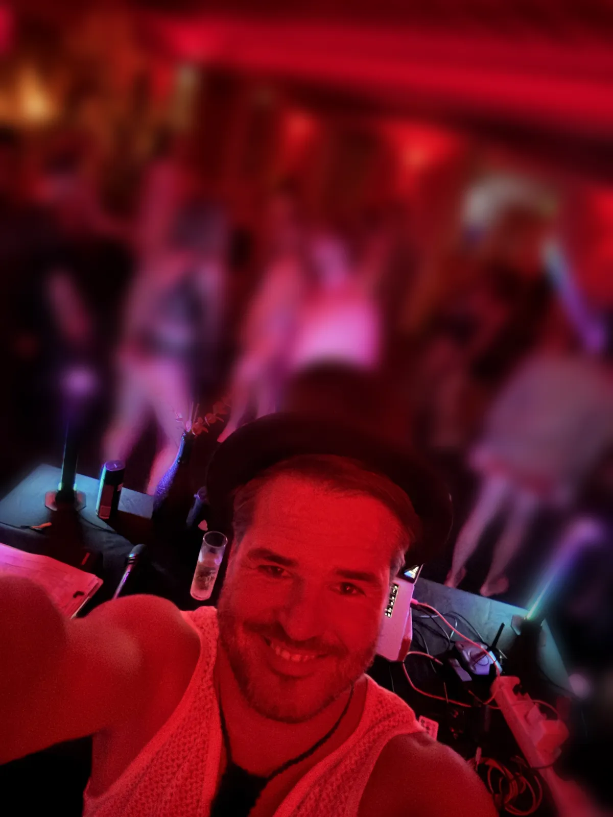 Robert at the DJ booth with the dancefloor behind him, guests softened for privacy