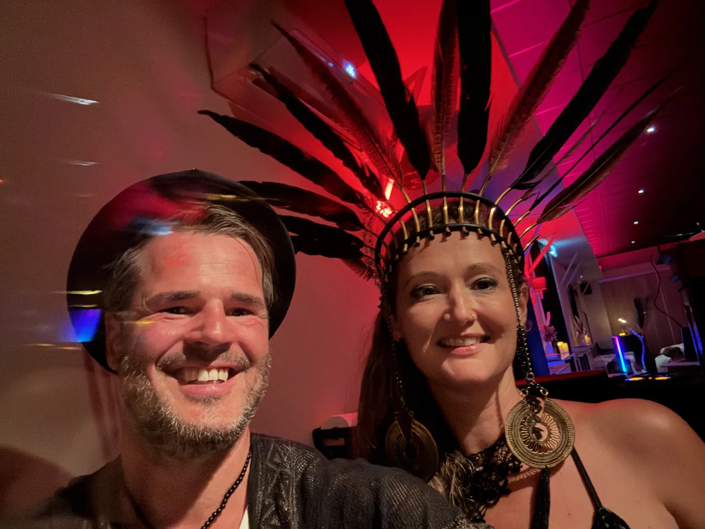 Veronique and Robert smiling in a feathered headdress and hat