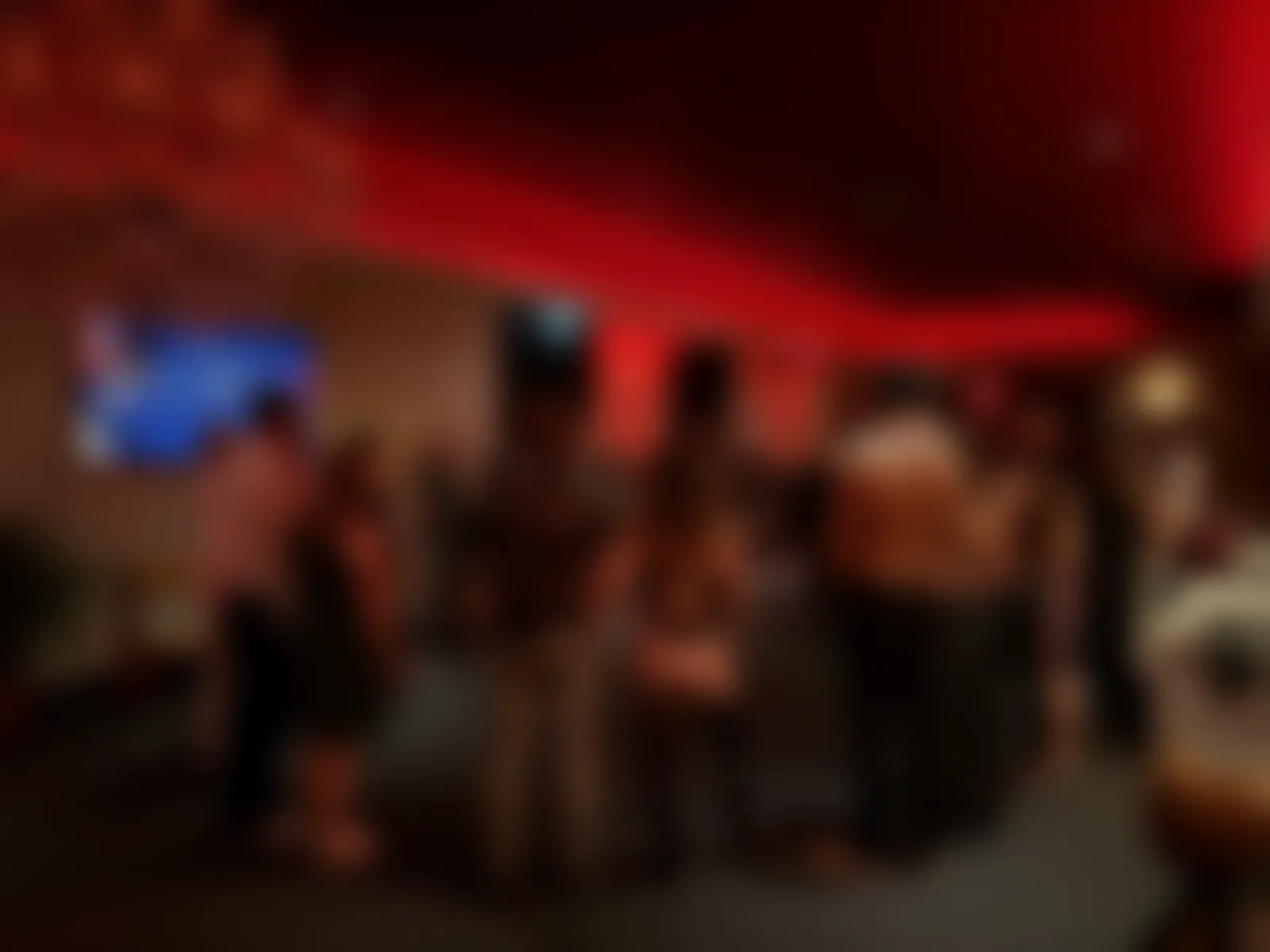 Guests gathering for a Sphere in red light, softened for privacy